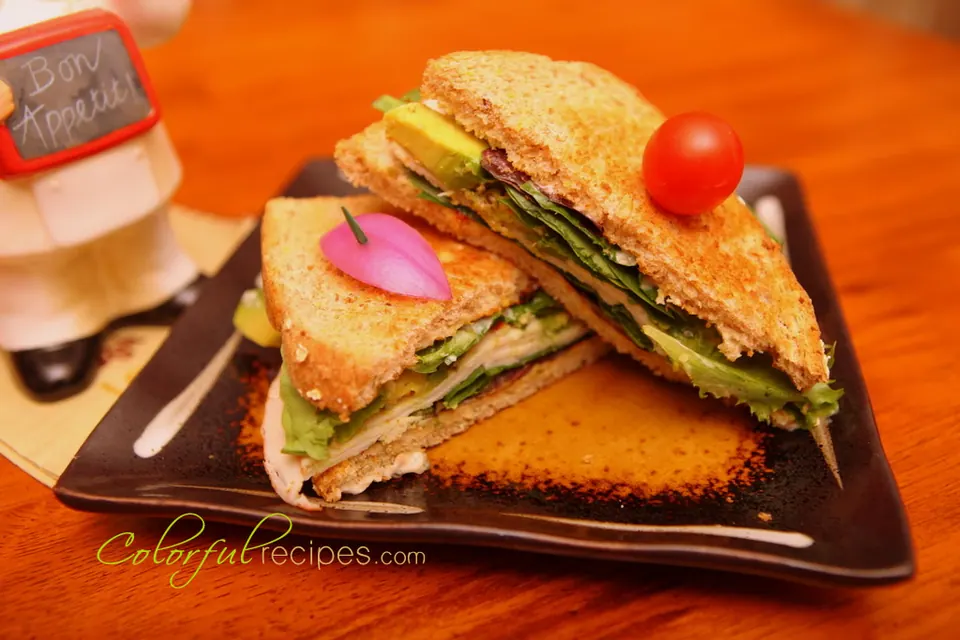 Turkey avocado sandwich on toasted whole grain bread with mixed greens