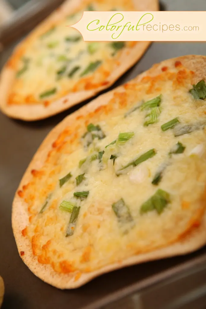 Golden baked cheese tortilla topped with melted mozzarella and green onions