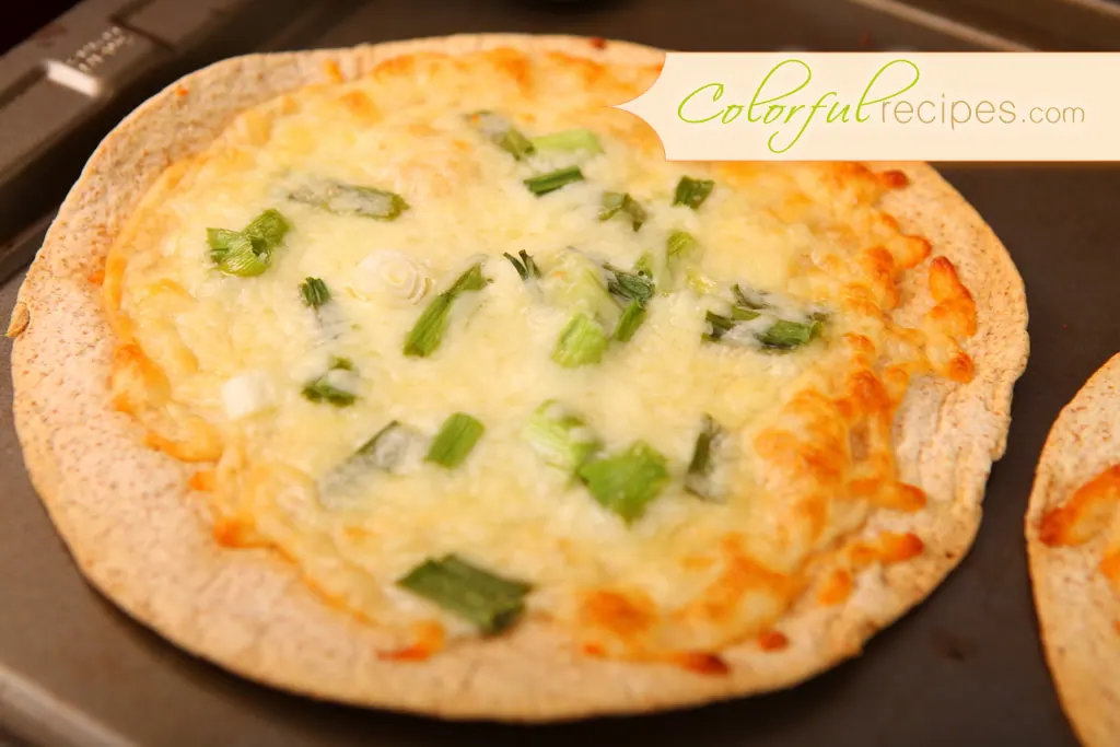 Baked cheese tortilla topped with melted mozzarella and chopped green onions