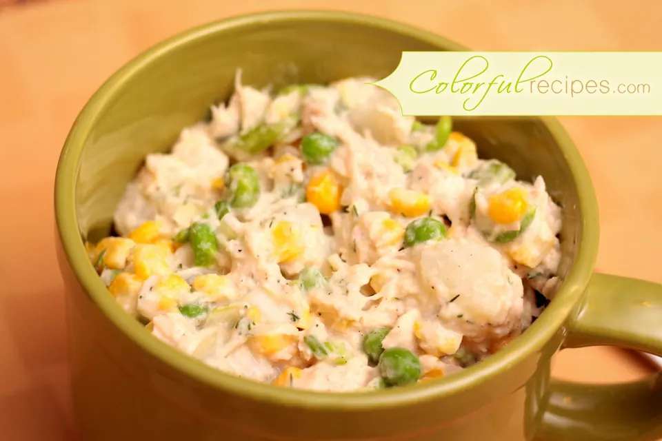 Tuna potato salad with corn, peas and dill in a green bowl
