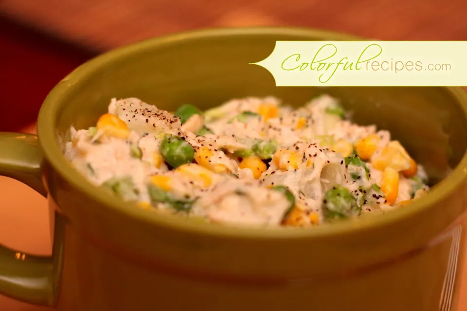 Bowl of tuna potato salad with corn and peas, sprinkled with black pepper