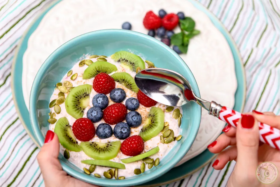 Spoonful of banana yogurt fruit breakfast bowl with berries and kiwi
