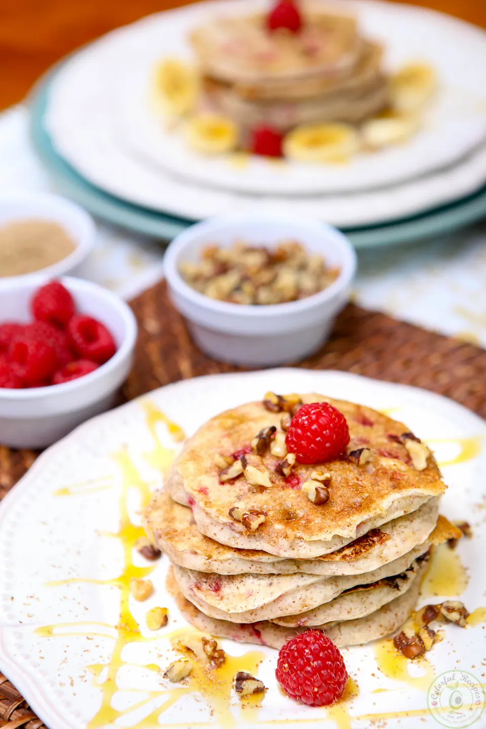 Stack of vegan flax raspberry pancakes topped with raspberries and chopped walnuts