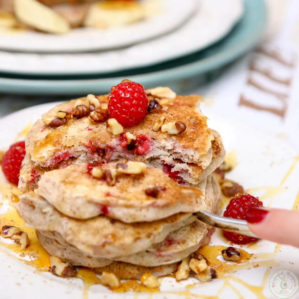 Vegan flax raspberry pancakes drizzled with maple syrup and topped with walnuts and a fresh raspberry