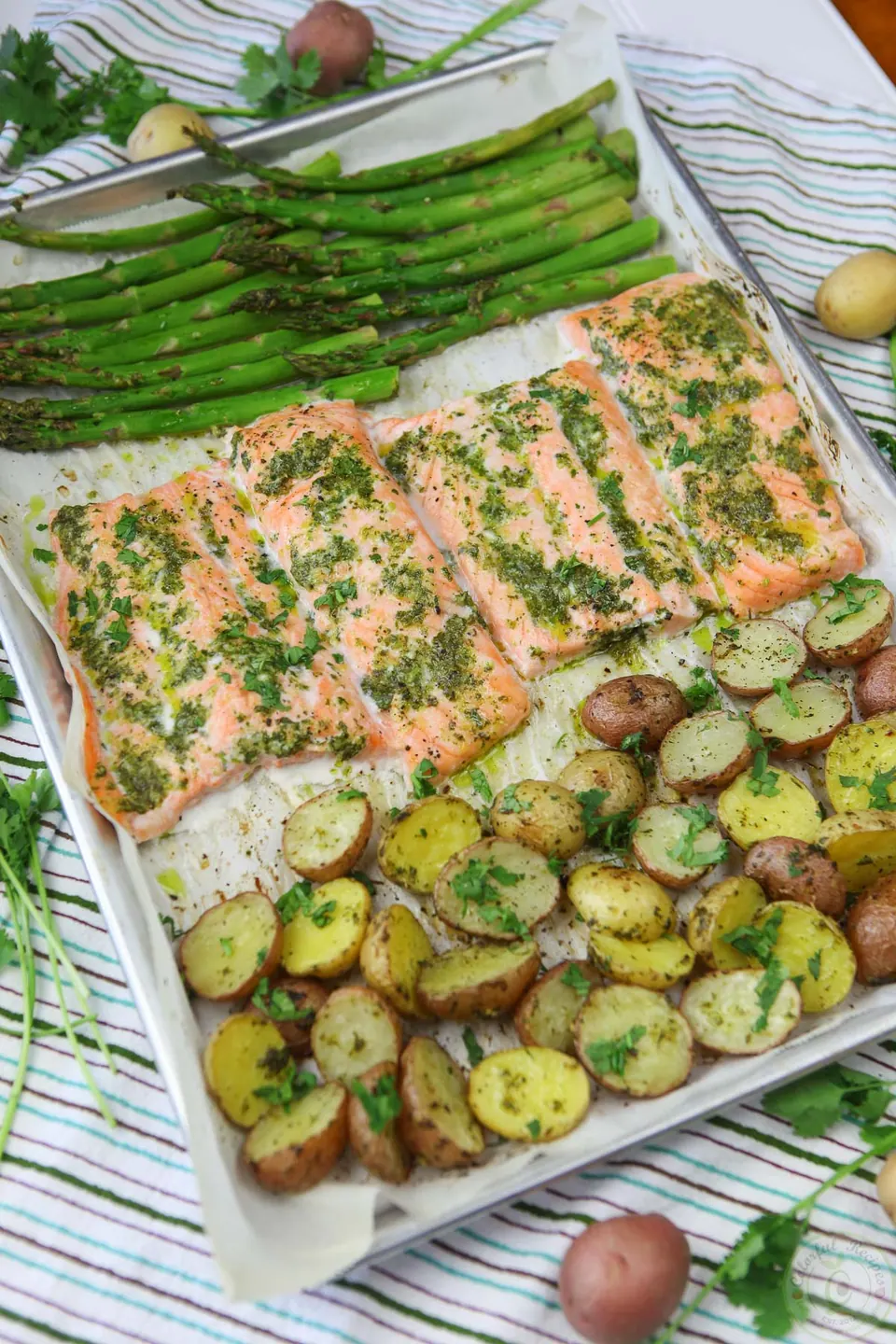 Sheet pan of salmon fillets, asparagus and baby potatoes with cilantro garlic citrus butter