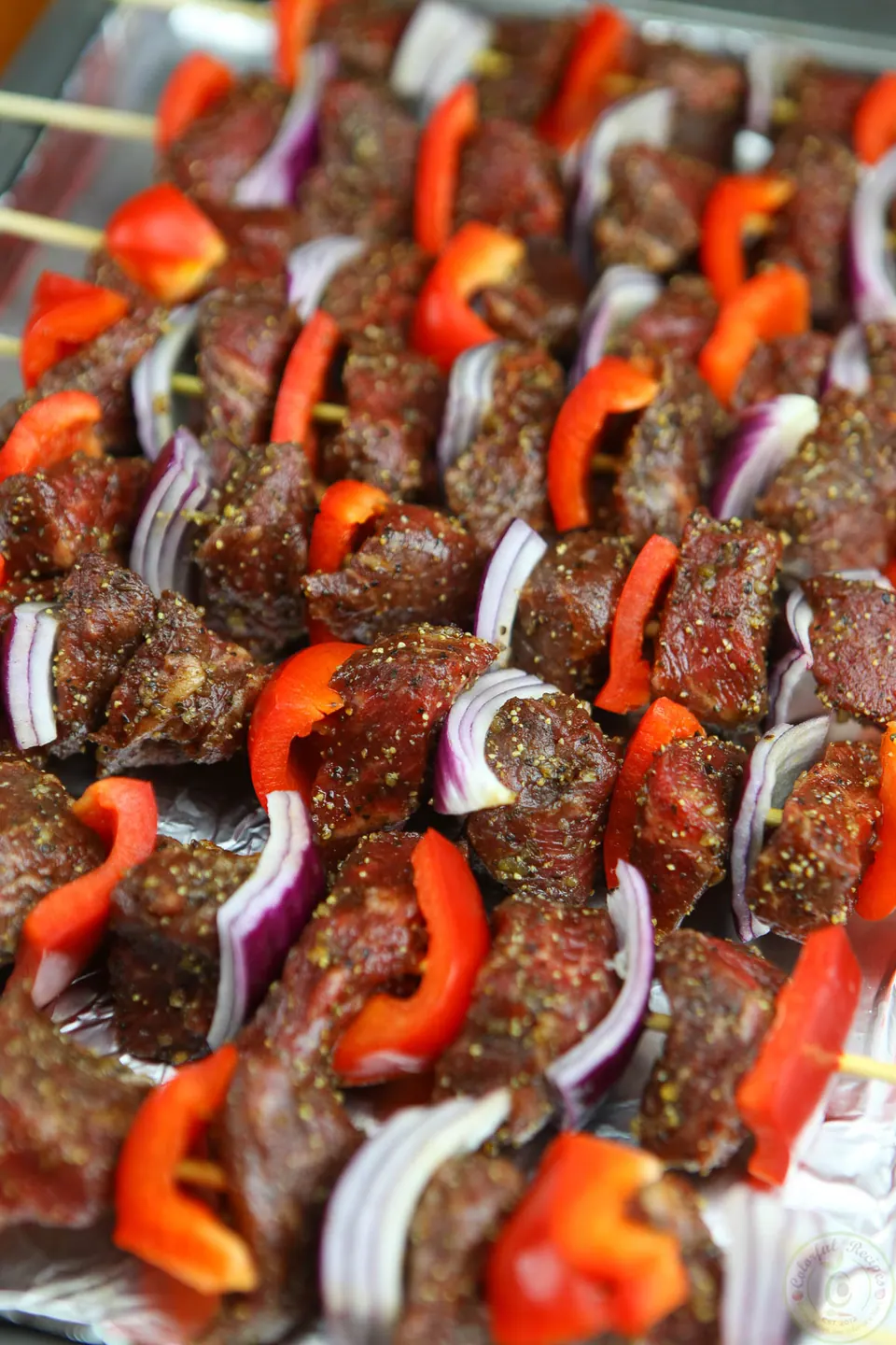 Oven broiled beef kabobs with red bell pepper and red onion on a foil-lined baking sheet